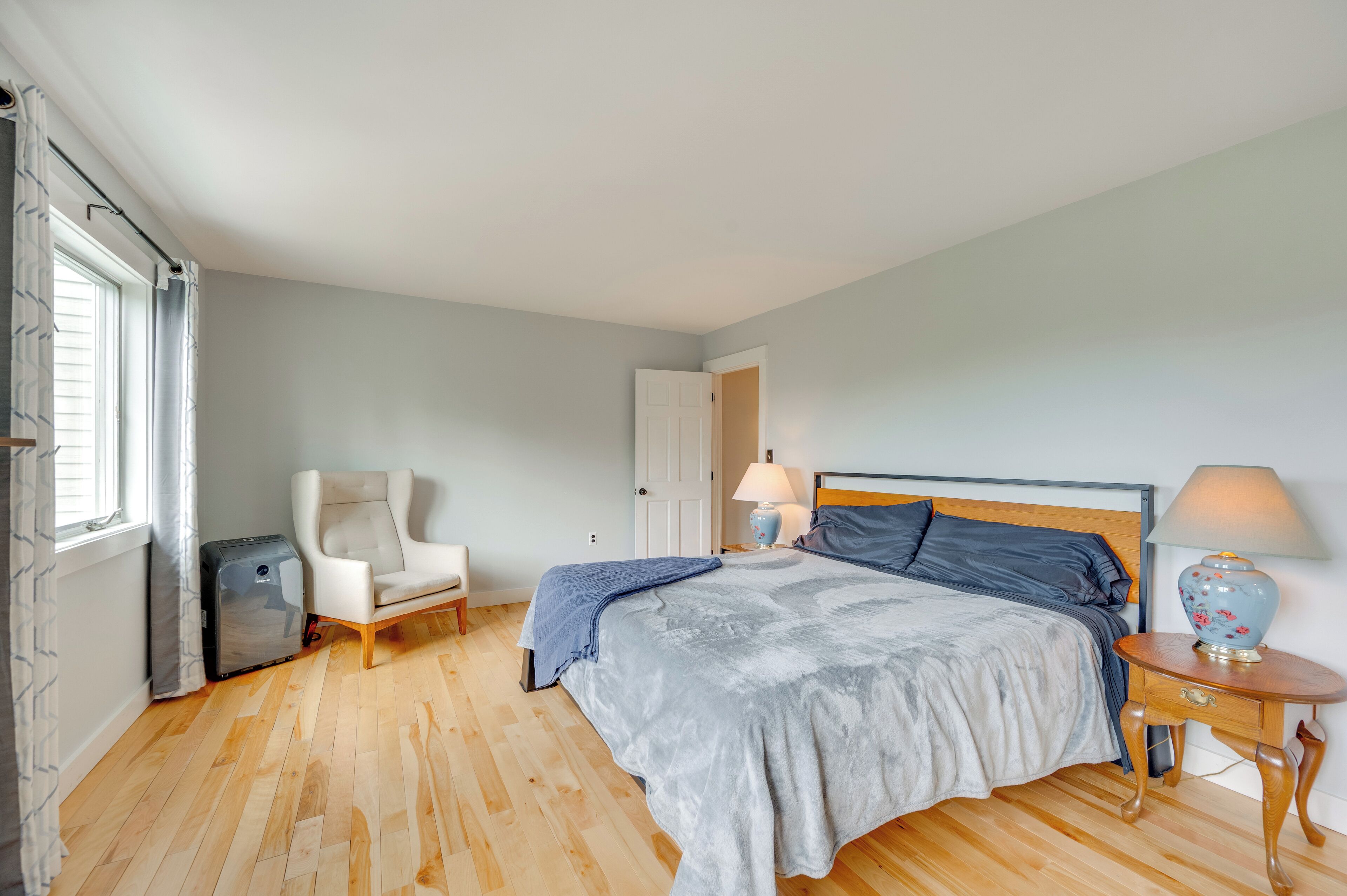 Une chambre à coucher avec un lit, une chaise, une table de chevet avec une lampe et une valise.