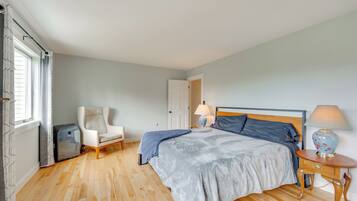 Une chambre à coucher avec un lit, une chaise, une table de chevet avec une lampe et une valise.