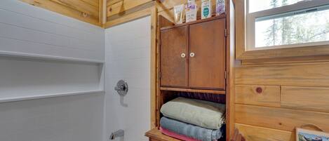Ein Badezimmer einer Holzhütte mit einer Badewanne, Holzschränken und einem Fenster.