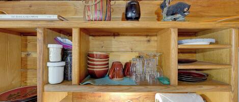 A wooden shelf with various items including a thermos, a small figurine, and a book titled 'The Trans Alaska Pipeline.'