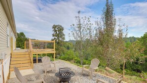 An outdoor patio with Adirondack chairs, a fire pit, and a wooden deck. - Deck w/ Mtn Views: Family-friendly Asheville Home! (Asheville)
