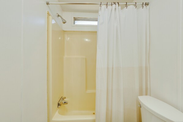 A bathroom with a bathtub, toilet, and a shower curtain. - Pets Welcome: Quiet Retreat Near Lake Guntersville (Langston)