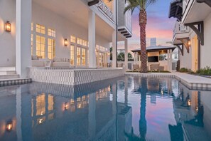 A pool with a view of a house, a palm tree, and a sunset. - 10,000+ Sq Ft Estate w/ Beach Access, Gulf Views, Pool, Pickleball, Bar (Inlet Beach)