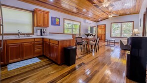 A spacious kitchen with wooden cabinets, a dining area with a table and chairs, and large windows allowing natural light. - Nemo's Loft: Panoramic 2BR/2BA Beachfront View in Ambergris Caye (San Pedro)