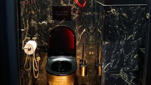 Een moderne badkamer met een marmeren wastafel, een toilet met houten onderstel, en een lijstwerk met een afbeelding van een hand die een roos vasthoudt.