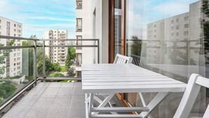 A balcony with a white table and chairs, overlooking a residential area with multiple apartment buildings. - P&O Apartments KEN (Warsaw)