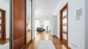 A hallway with wooden flooring, a white rug, a sofa, and a cabinet. - P&O Apartments KEN (Warsaw)