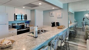 Una cocina moderna con encimera de mármol, electrodomésticos de acero inoxidable y una zona de bar con taburetes.