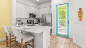 A modern kitchen with white cabinets, a central island, and a teal door. - Savannah Daydreamin - For 6 (Kissimmee)