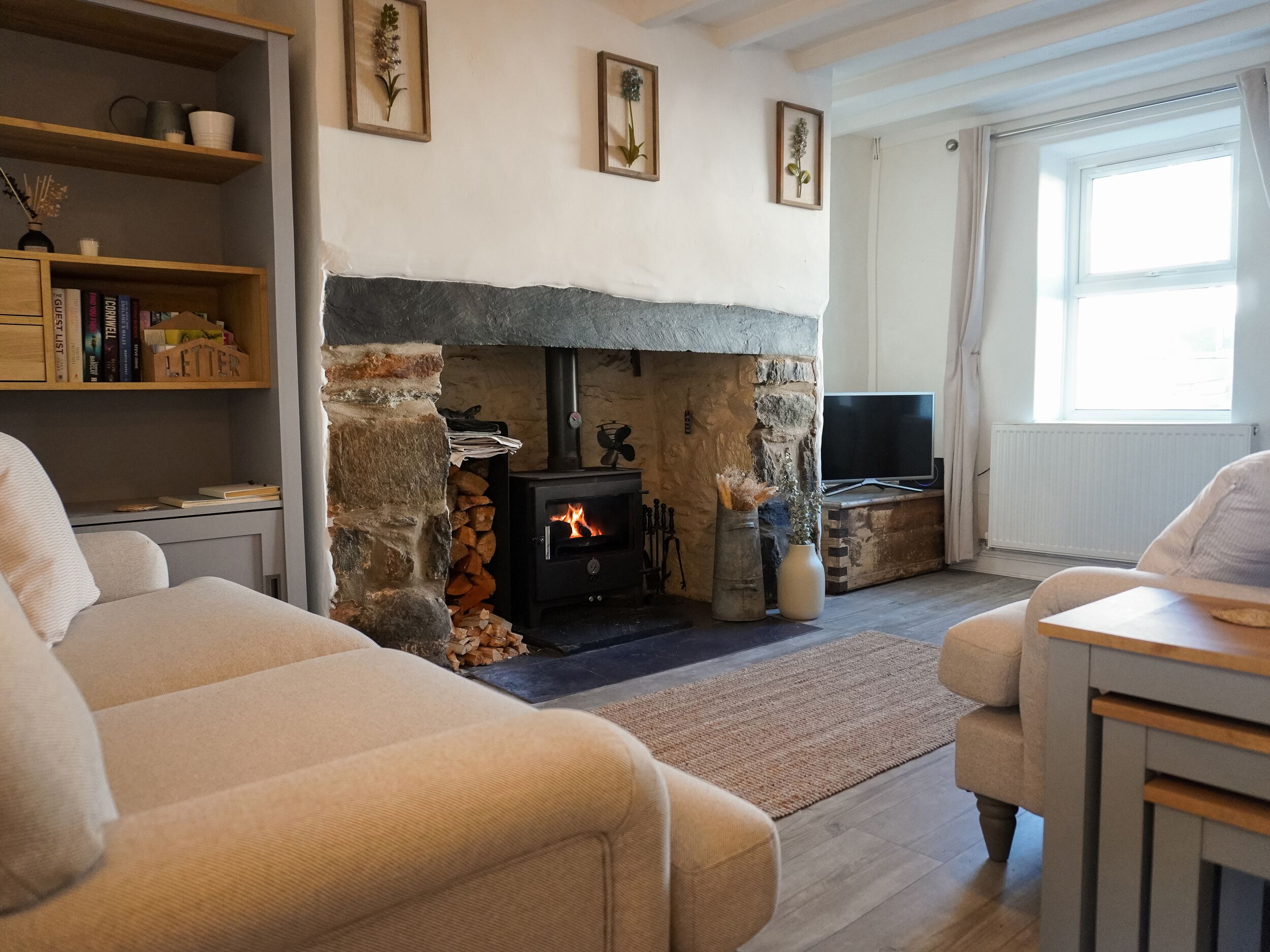 A cozy living room with a stone fireplace, a bookshelf, a television, and comfortable seating.