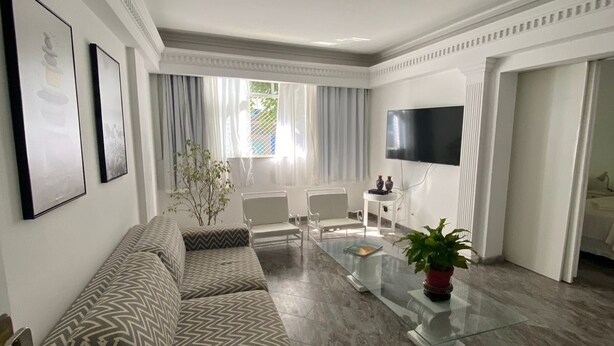 Una sala de estar moderna con un sofá, sillas, una mesa de centro y una televisión.