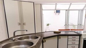 Una cocina moderna con un lavamanos doble, armarios blancos y un ventanal que proporciona luz natural.