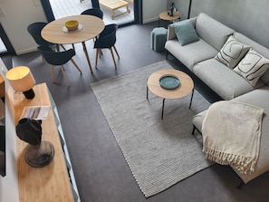 Un salon moderne comprenant un canapé, une table basse, une table à manger avec des chaises et une petite table d’appoint.
