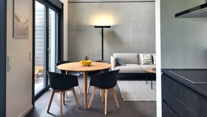 Un interior moderno con una mesa redonda de madera, sillas negras, un sofá y una lámpara de pie.