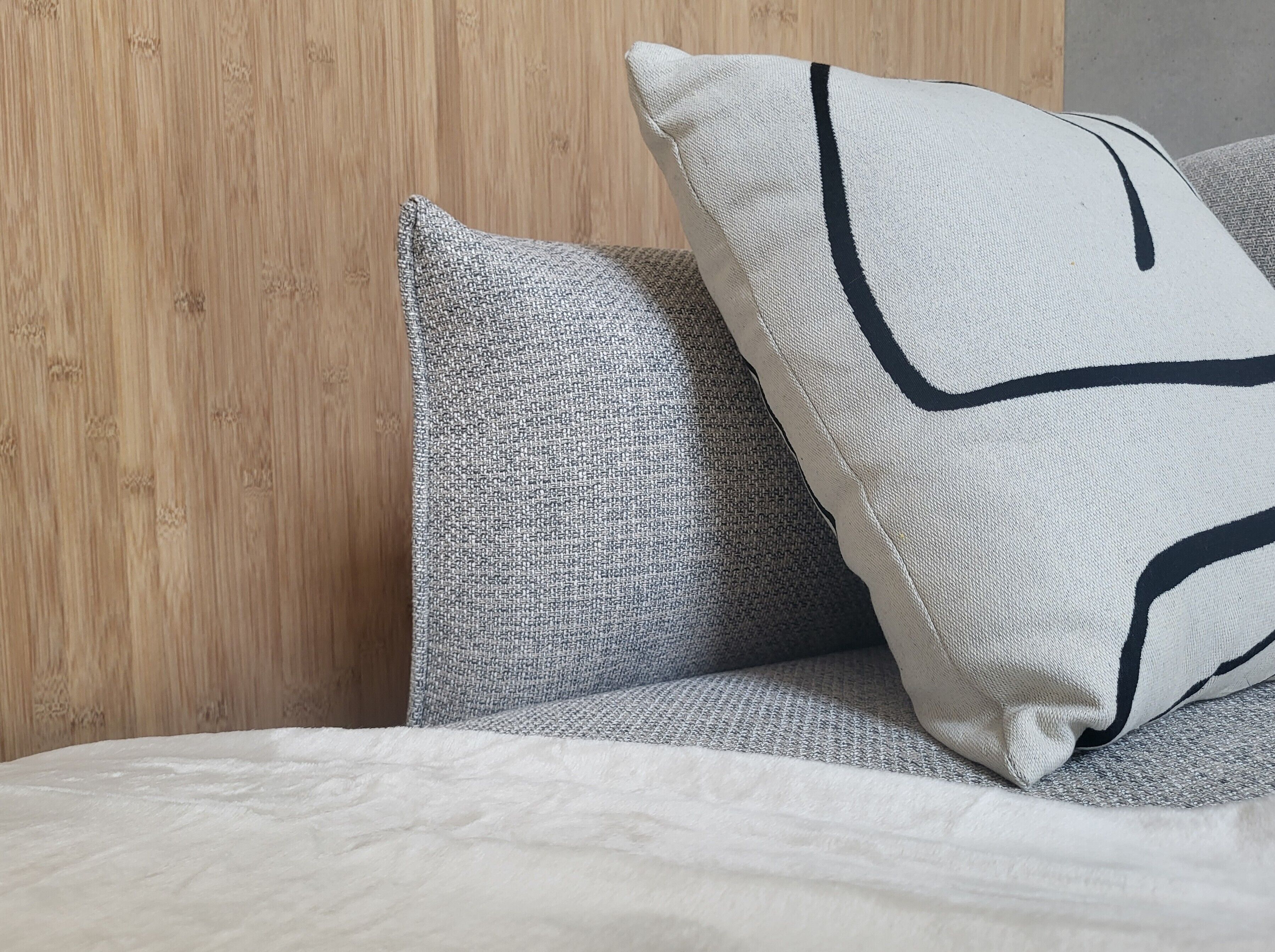 Un lit avec une couette blanche et deux oreillers, dont l’un est orné d’un motif noir.