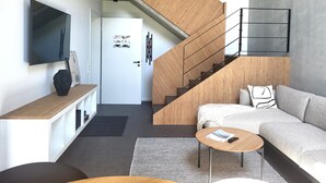 Un salon moderne avec un escalier, un téléviseur à écran plat, un canapé et une table basse.
