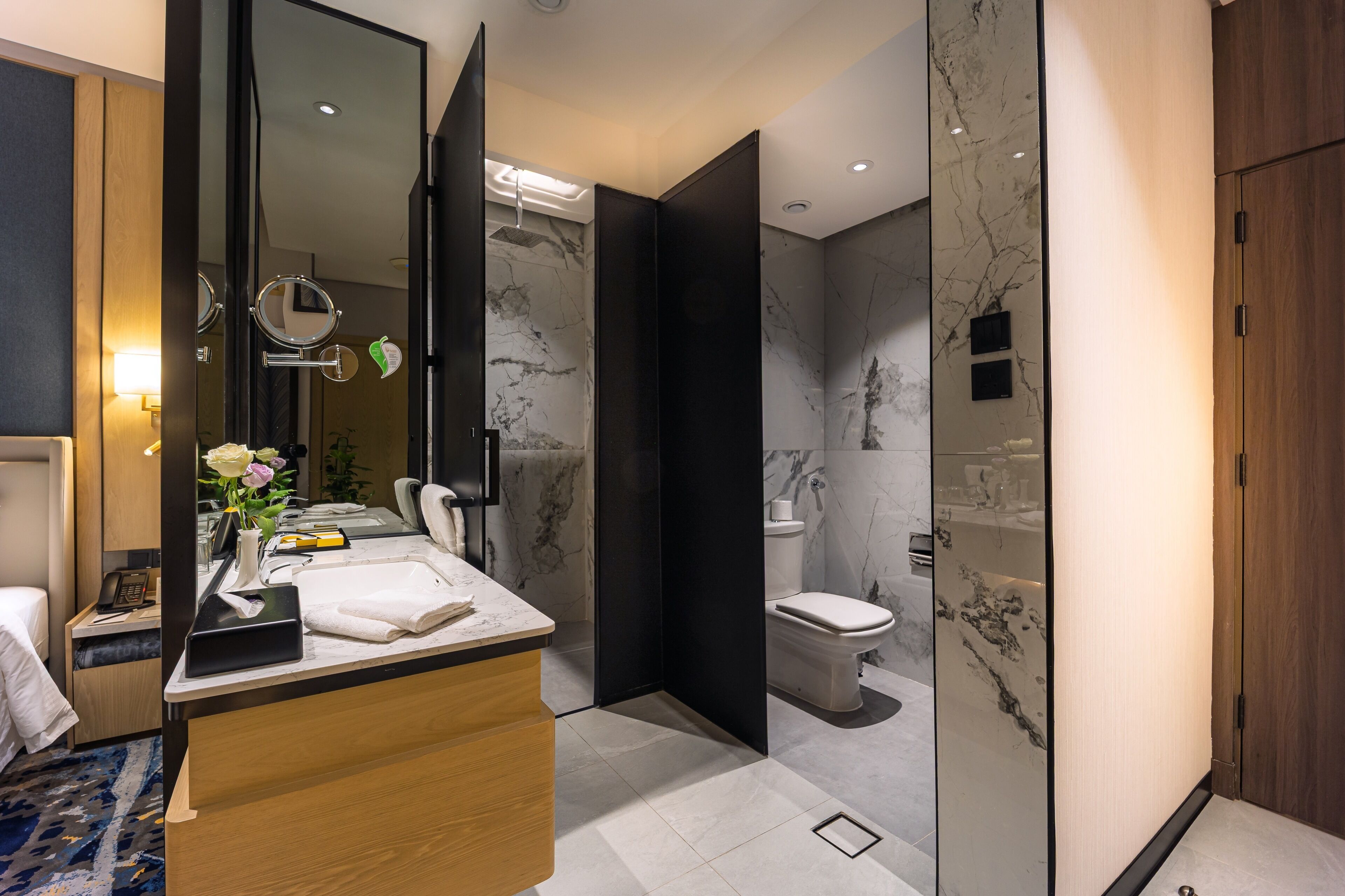 Un baño moderno con tocador de mármol, espejo, inodoro y zona de ducha.