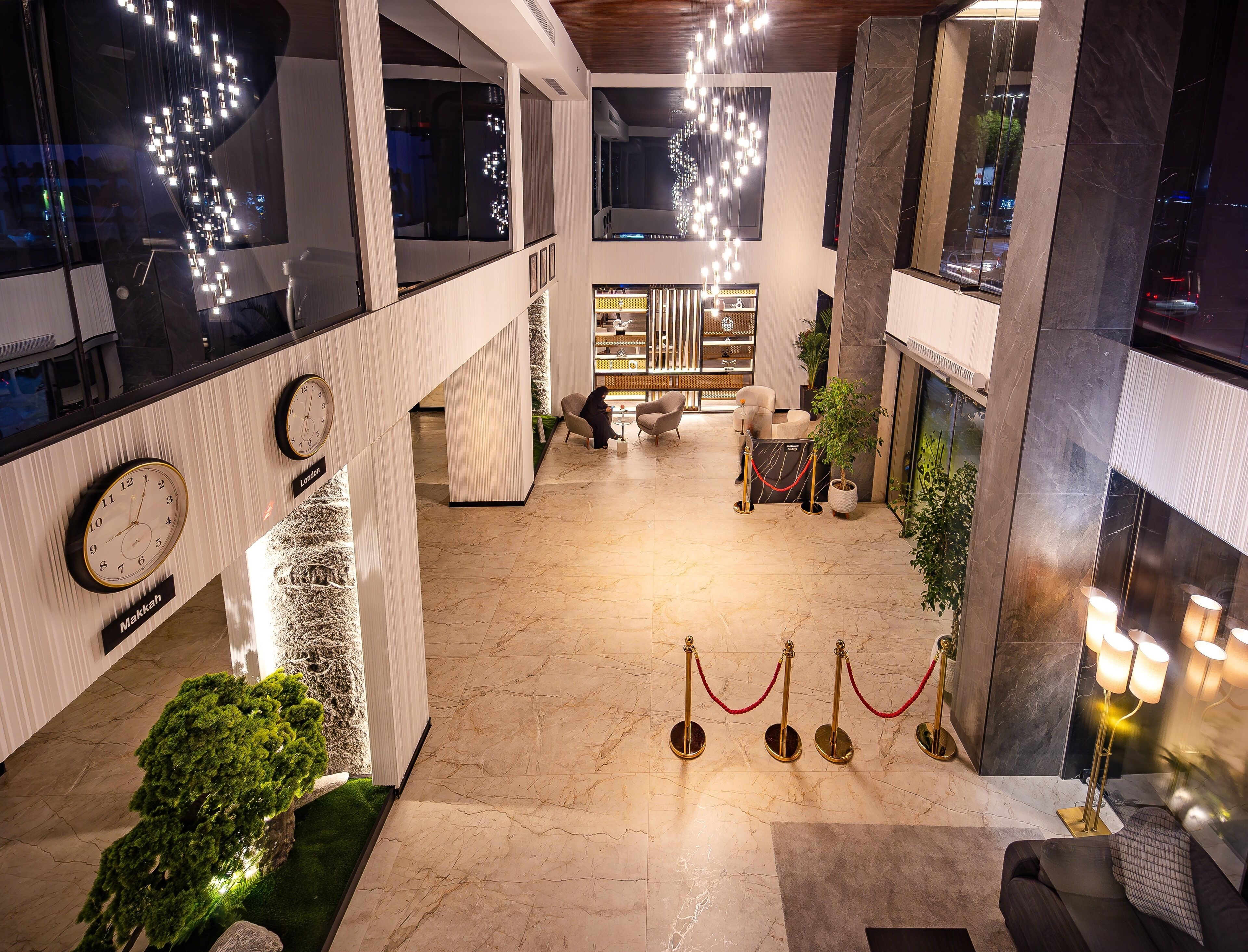 Um hall amplo com teto alto, luminárias modernas e área de estar com sofá e poltronas.