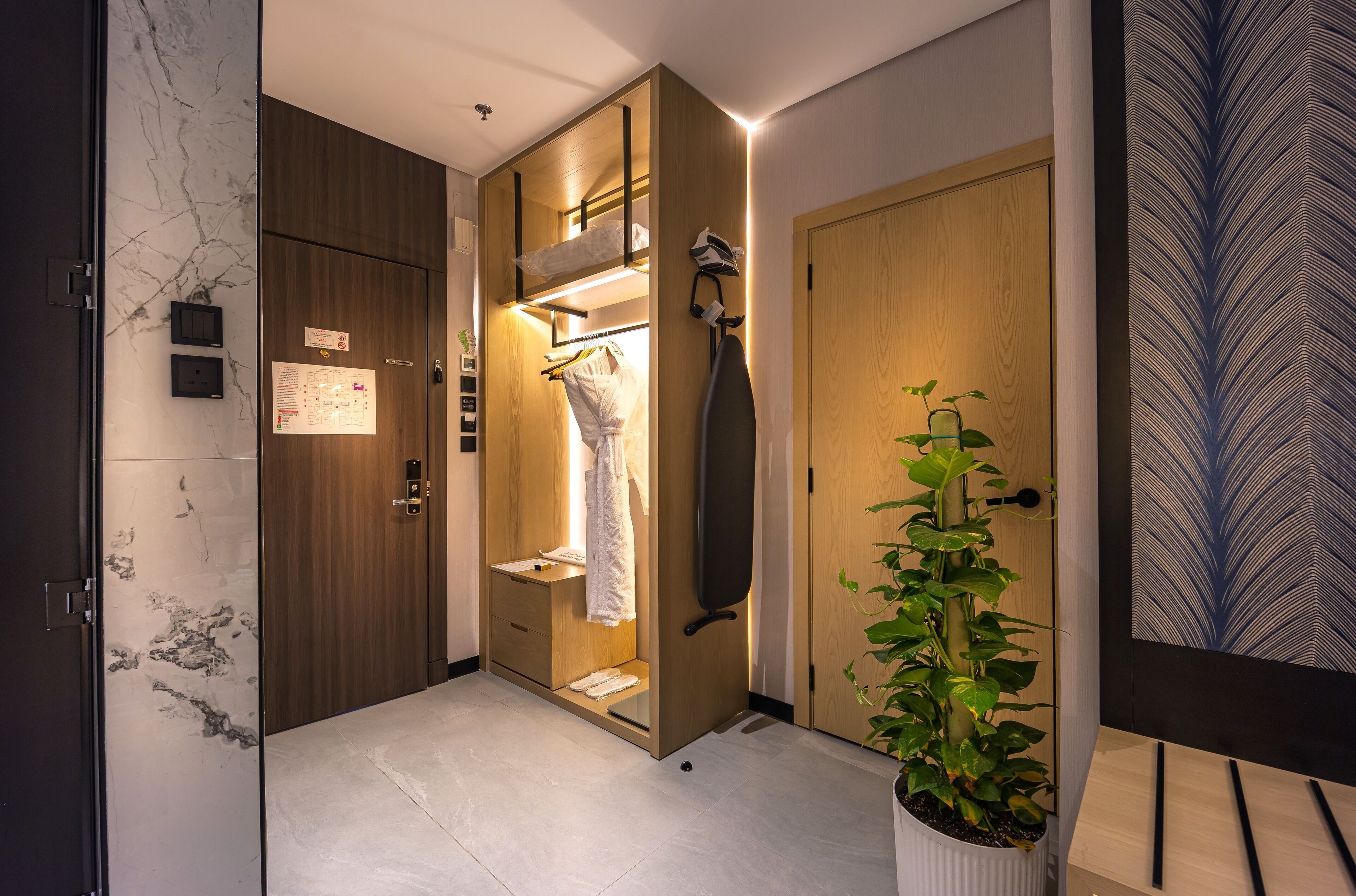 Un baño moderno con tocador de madera, un perchero y una planta en maceta.