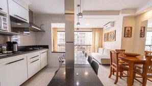Una cocina moderna con armarios blancos, encimera negra y zona de comedor con mobiliario de madera.