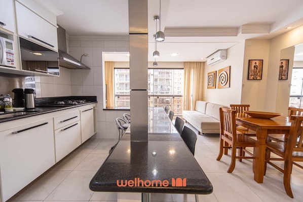 A modern kitchen with white cabinets, a black countertop, and a dining area with wooden furniture.