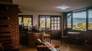 Una cocina acogedora con pared de ladrillo, un comedor con mesa y sillas, y un amplio ventanal con vistas al exterior.