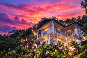 A two-story building with balconies, surrounded by lush greenery and flowering plants. - Nature Harmony (Udumbanchola)
