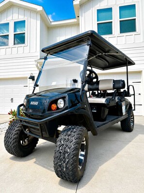 A golf cart with a canopy, large tires, and a logo on the front.