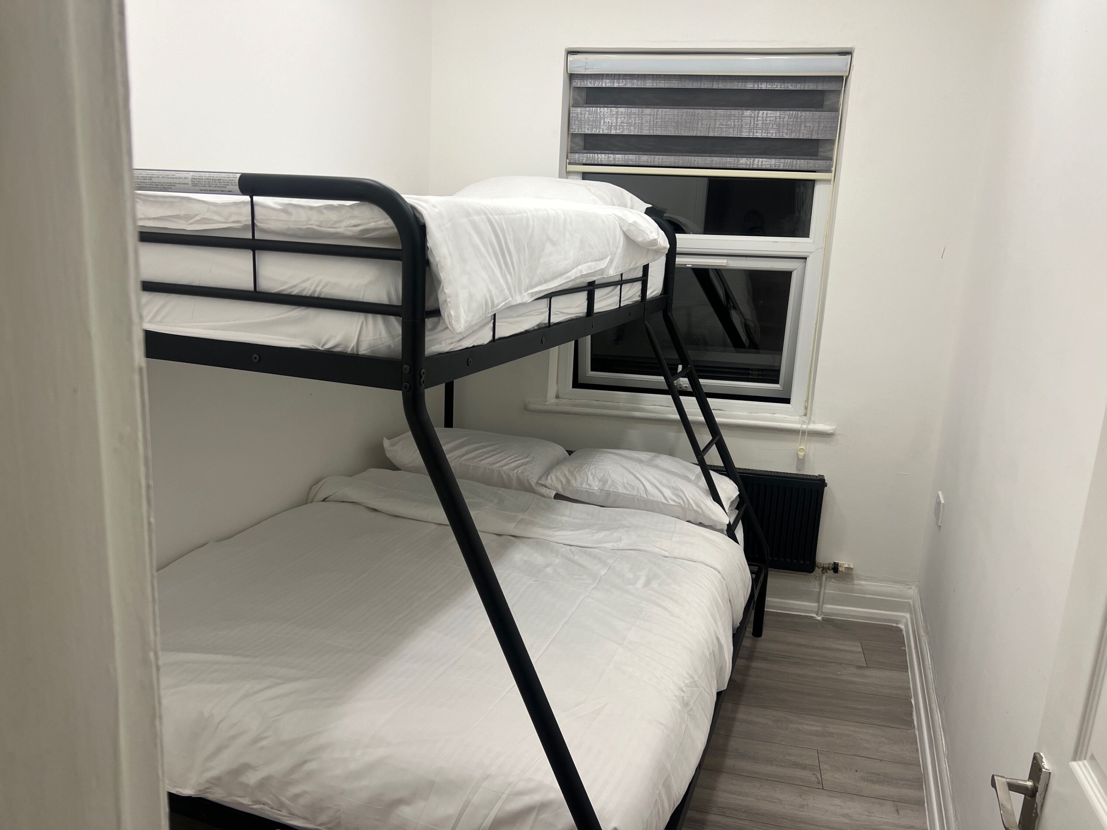 A bunk bed room with a window and radiator.