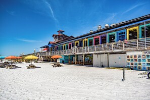 Edificio sul lungomare con pareti esterne colorate, un balcone e posti a sedere all'aperto con ombrelloni.