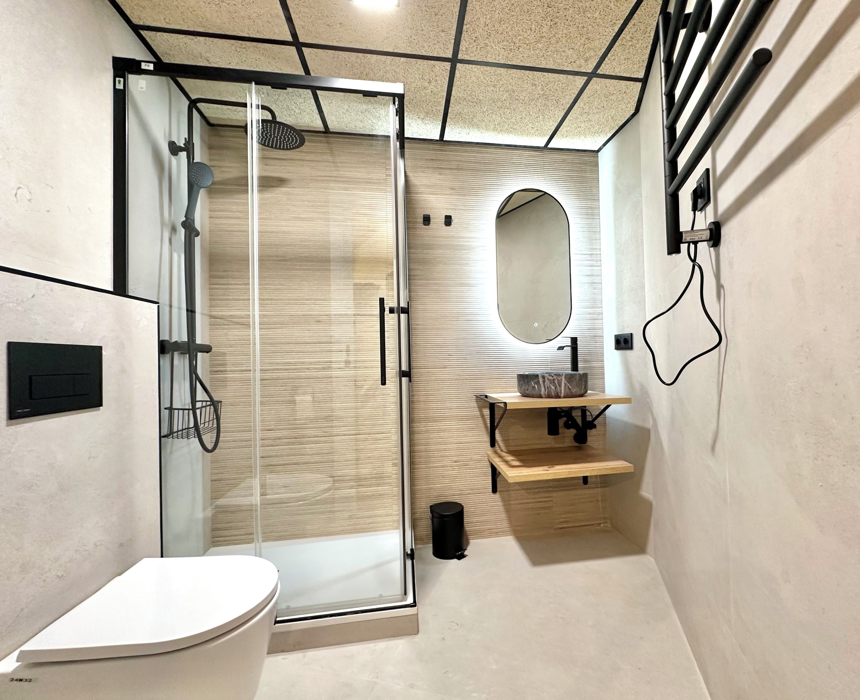 Une salle de bain moderne avec une douche à parois de verre, des toilettes blanches et un meuble-lavabo en bois avec un miroir.