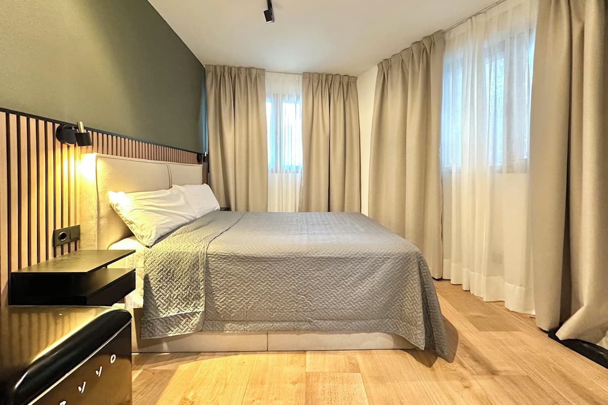 Ein modernes Schlafzimmer mit einem Bett, einem Nachttisch und einem Kopfteil mit vertikalen Linien.