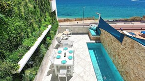 Una terraza en la azotea con piscina, mobiliario exterior y vistas al océano.