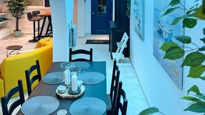 Un espacio habitable con temática marina, que incluye un comedor, cocina y una puerta azul.