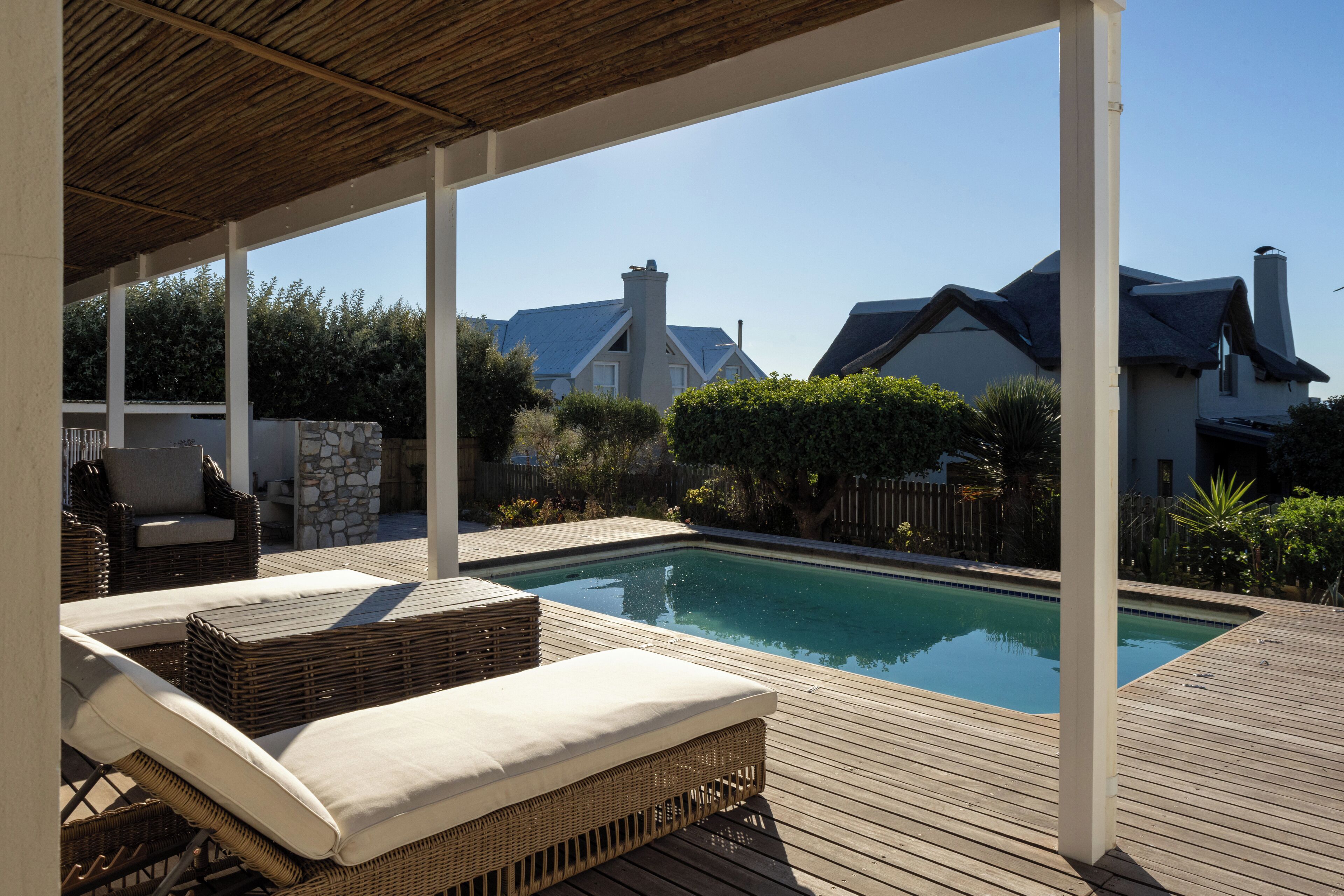 Un área de piscina exterior cubierta con sillones reclinables y un muro de piedra.