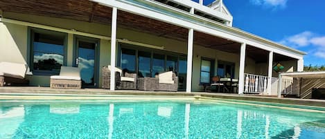 A modern house with a swimming pool, large windows, and outdoor furniture.