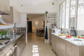 Una cocina moderna con una isla central, electrodomésticos de acero inoxidable y un área de comedor al fondo.