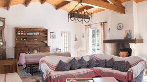 A cozy room with a sofa, a wooden cabinet, a fireplace, and a dining area. - Villa Kenavo - Family house with sea view (Île-d'Aix)