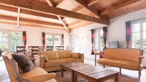 A spacious living room with wooden beams, a sofa, chairs, a wooden coffee table, and a television. - Marais Aixois-Villa-Villa-Ensuite Bathroom-View of the (Île-d'Aix)