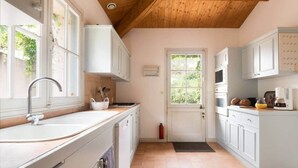 A kitchen with white cabinets, a sink, a stove, and a door with a window. - Marais Aixois-Villa-Villa-Ensuite Bathroom-View of the (Île-d'Aix)