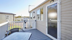 A covered outdoor area with a table and chairs, a white fence, and a sliding glass door. - Host & Stay | Leon's Retreat (Cresswell)