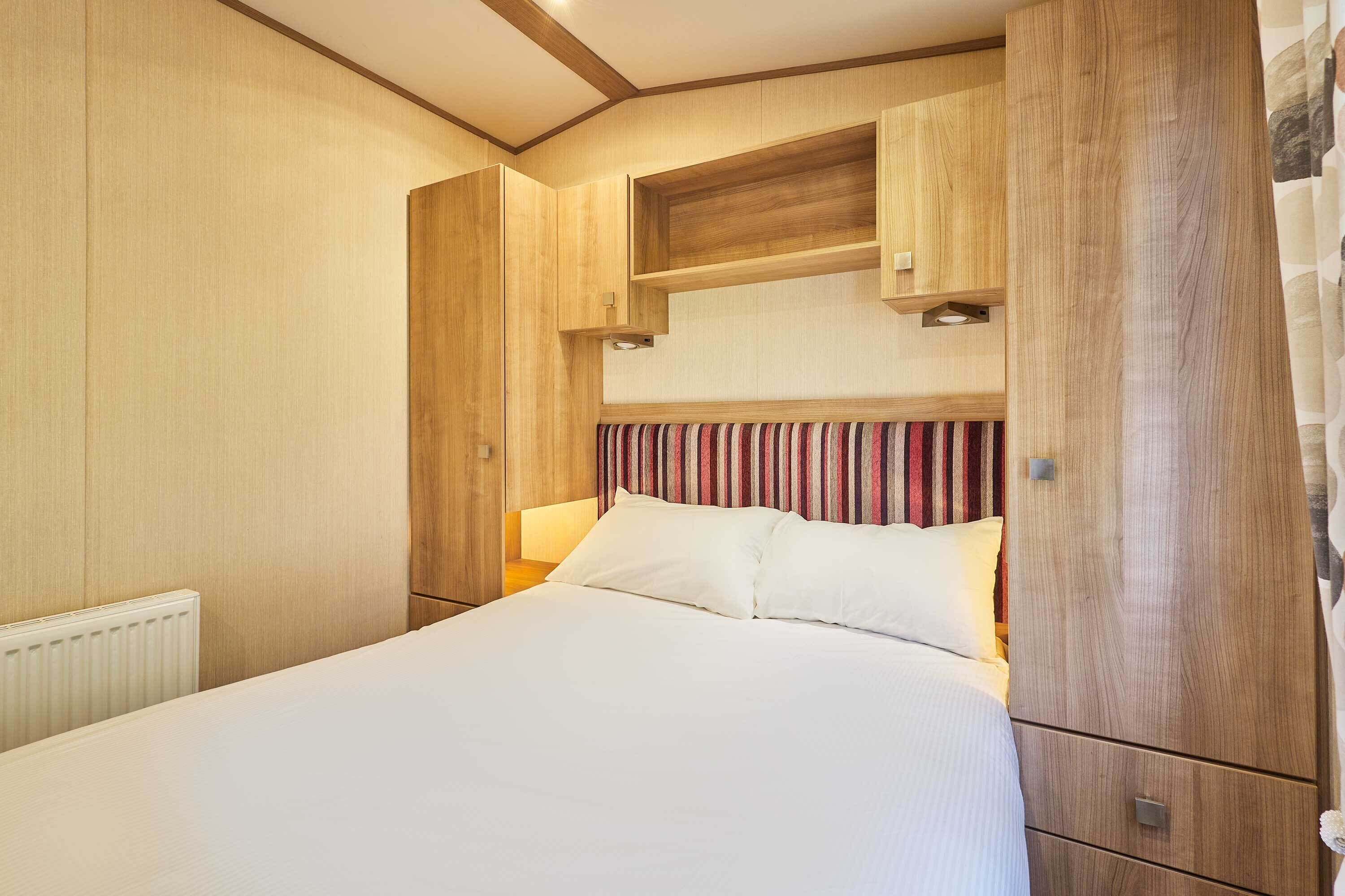 Ein Schlafzimmer mit einem großen Bett, einem hölzernen Kopfteil und eingebauten Stauraumschränken.