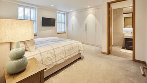 A bedroom with a bed, a bedside lamp, a TV, and a wardrobe. - Host & Stay | Thames Apartment (Windsor)