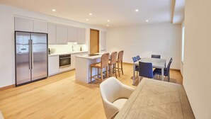 A modern kitchen with a central island, bar stools, and a dining table with chairs. - Host & Stay | Thames Apartment (Windsor)