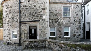 Ein Steinhaus mit einer schwarzen Tür, auf der steht: "First Floor Apartments".