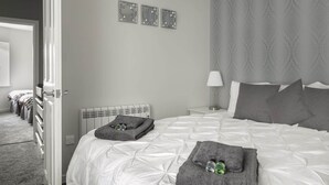 Ein Hotelzimmer mit einem ordentlich bezogenen Bett, einer Nachttischlampe und einer Heizung.