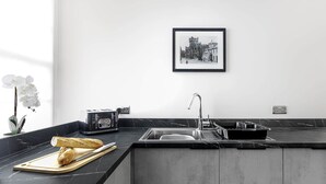 A modern kitchen with a marble countertop, a built-in sink, and a black and white photograph on the wall. - Scalpsie Luxury Apartment (Rothesay)