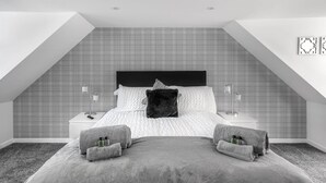 A bedroom with a bed, two nightstands, a black headboard, and a plaid-patterned wall.