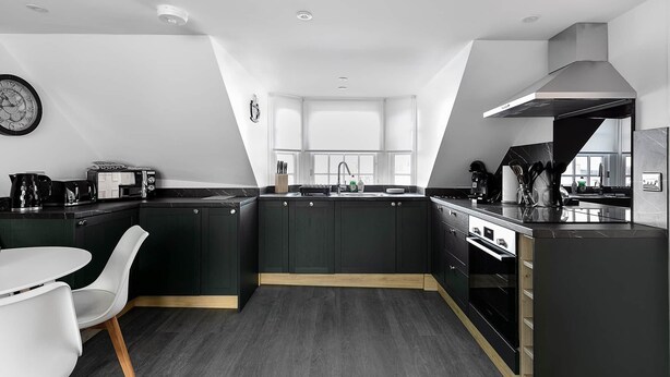 A modern kitchen with dark cabinetry, a white countertop, and a built-in oven.