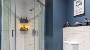 A bathroom with a glass-enclosed shower, a toilet, and a sink.